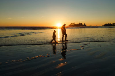 Father and son walking in the surf at Chesterman Beach in Tofino, British Columbia