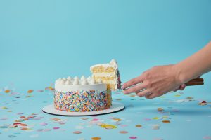 Partial view of woman taking piece of delicious cake on blue background